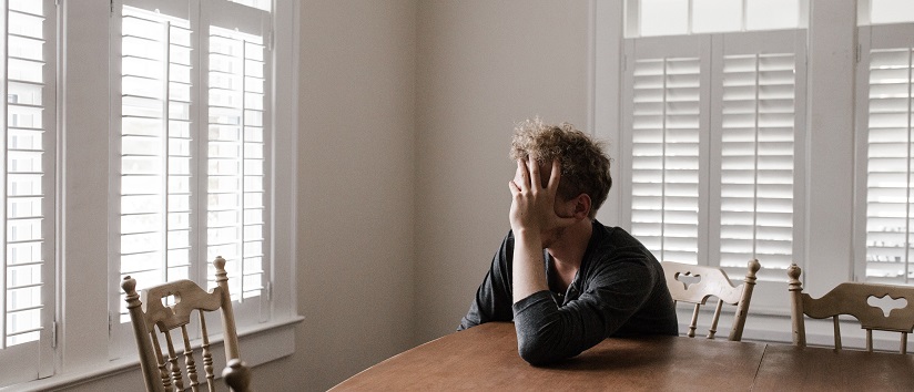 Man sat alone at a table, looking out the window