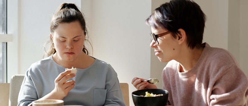 woman eating breakfast with young person with Down syndrome