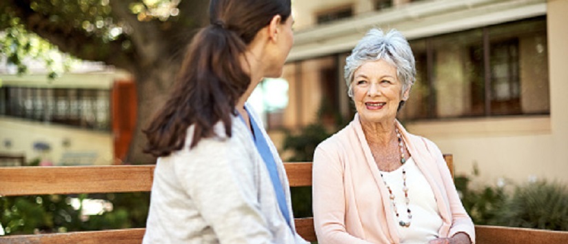 Shot of a senior woman and a nurse sitting together on a bench out in the garden